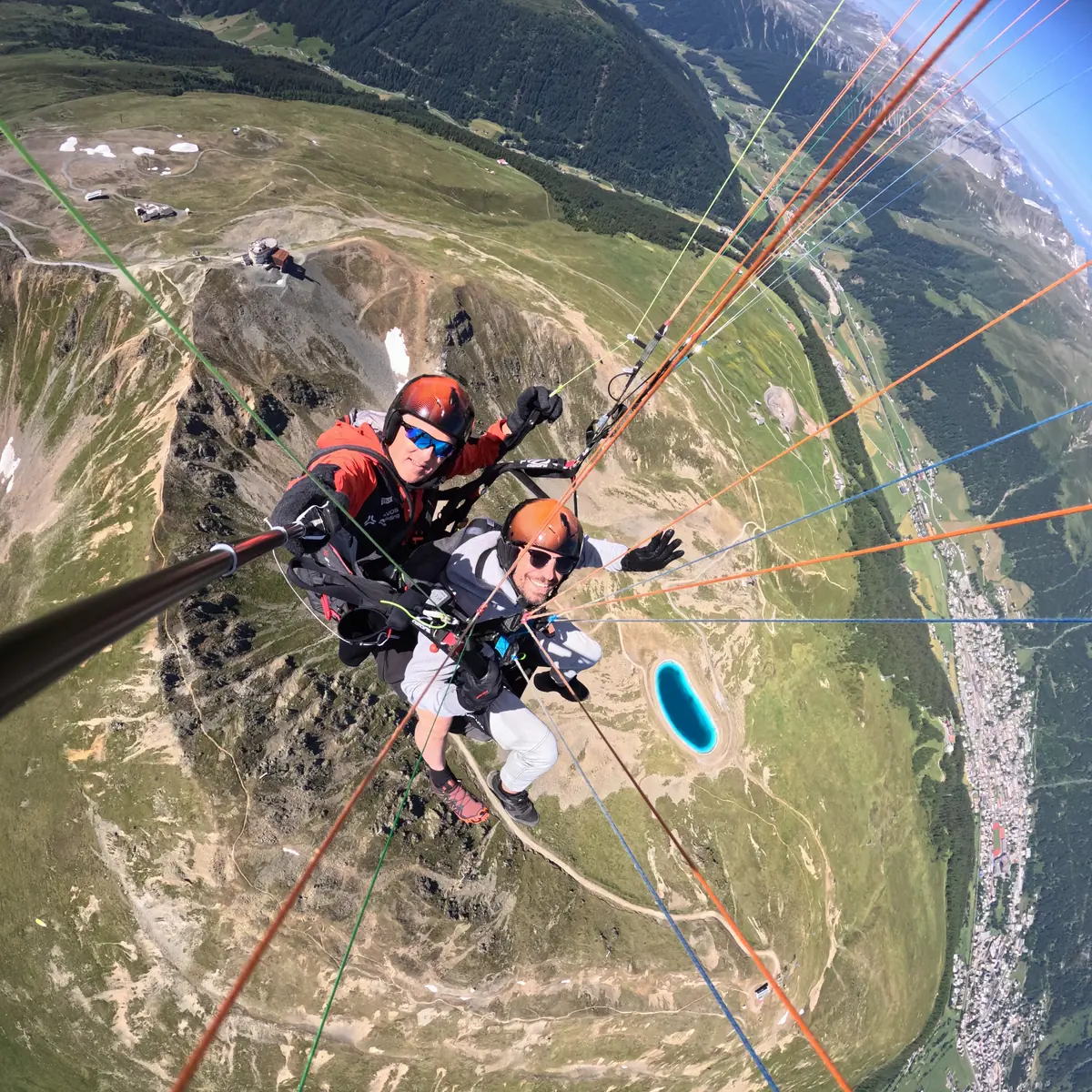 Tandem-Gleitschirmflug hoch über dem Jakobshorn: Pilot und Passagier über Davos, tief unten der Schwarzsee und das Tal
