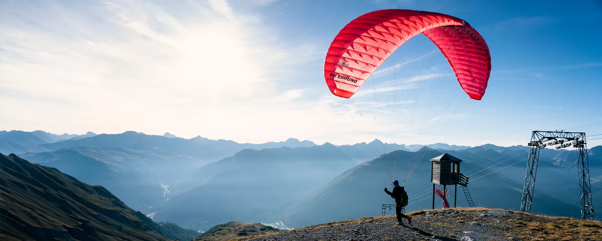 Pilot zieht den roten Gleitschirm am Startplatz über dem Tal von Davos auf