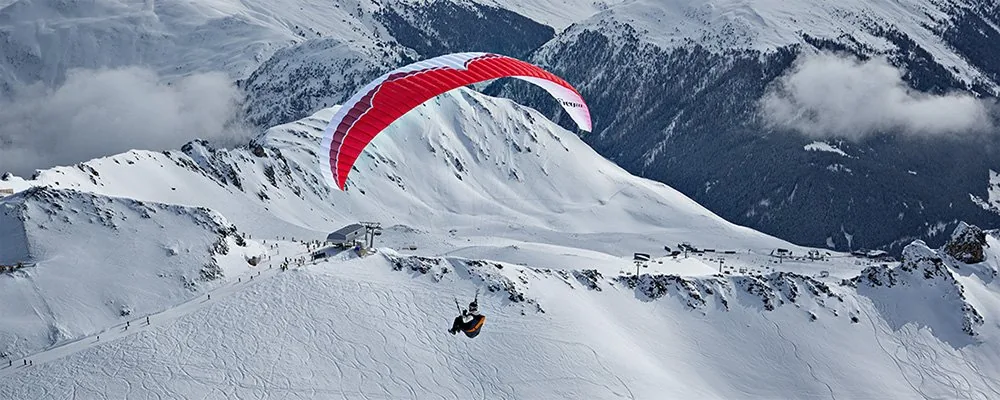 Gleitschirmstart am Weissfluhgipfel im Parsenn-Gebiet über den verschneiten Bergen von Davos