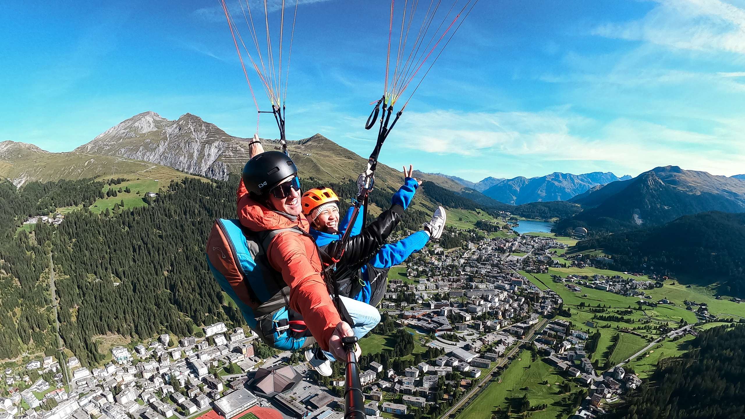 Tandem-Gleitschirmflug hoch über Davos: Gast und Pilot vor Bergpanorama und Davosersee