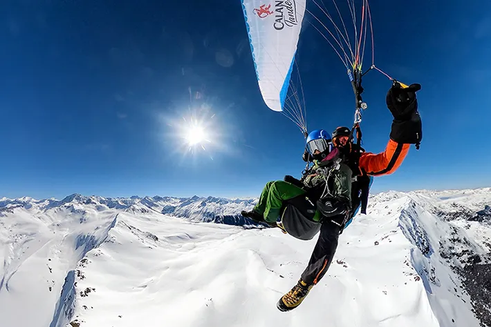 Winter-Tandem-Paraglidingflug über die tiefverschneite Landschaft von Davos während eines Thermikflugs vom Jakobshorn